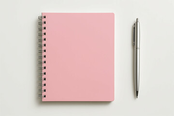 A pink spiral notebook and a silver pen are neatly placed on a clean, light-colored surface.