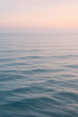 Obraz premium Tranquil ocean at sunset with gentle waves and pink sky