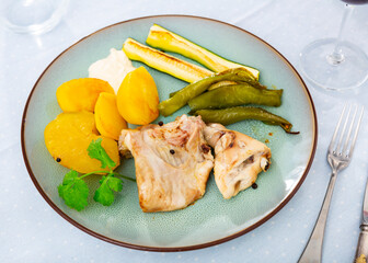 Portion of just cooked rabbit with vegetables. Rabbit meat garnished with potato, zucchini and bell pepper.