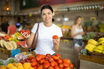 Adult woman buyer choosing fresh tomatoes in vegetable shop