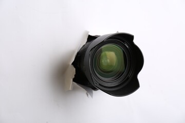 Hidden camera lens through torn hole in white paper