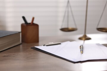 Judge. Scales, book, papers and pen on wooden table in office, closeup