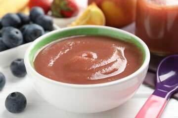 Baby food. Tasty puree in bowl, spoon and ingredients on white wooden table, closeup