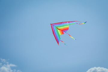 Colorful kite flying in blue sky, low angle view. Space for text
