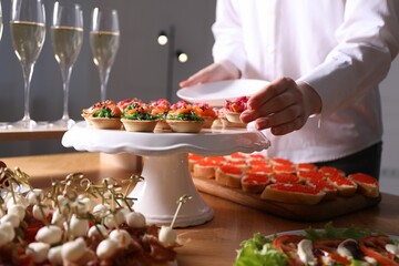 Buffet menu. Woman taking tasty tartlet from table, closeup
