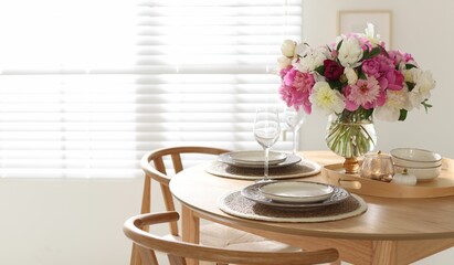 Beautiful table setting with bouquet of peonies in dining room. Space for text