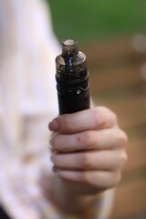 Young woman with electronic smoking device outdoors, closeup