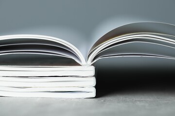 Stack of different magazines on grey table, closeup