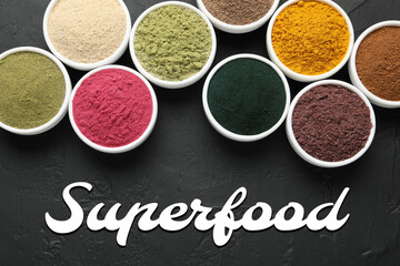 Superfood. Different powders in bowls on black table, flat lay