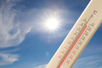 Extremely high temperature on thermometer against blue sky on sunny day. Summer weather