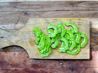 Sliced ​​fresh green bitter melon vegetables on a wooden cutting board isolated on a wooden...