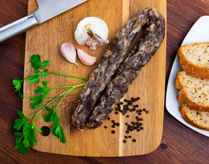 Traditional Spanish cured pork sausage on a wooden chopping board with garlic, peppercorns and a...