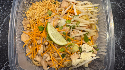 Chicken Pad Thai noodles in a takeout container, a popular Thai food dish