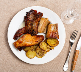 Appetizing roasted rabbit pieces with vegetable garnish of fried potatoes. Delicious and satisfying homemade dinner..
