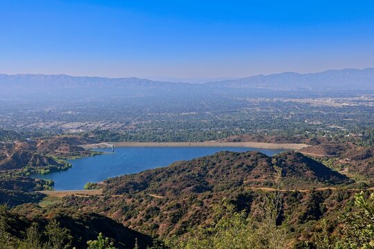 The Hollywood Hills fade into the San Fernando Valley with the San Gabriel Mountains and Santa Susana Mountains in the background and the Encino Reservoir in the foreground
