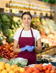 Portrait of female seller in apron in interior of grocery supermarket