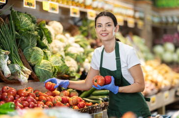 Shop seller put goods on display case. Girl creates stock of tomato in display case, forms...