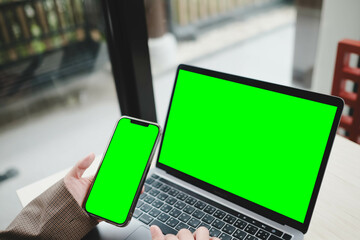 A person using a laptop and smartphone, both with blank green screens. A dual-device chroma key...