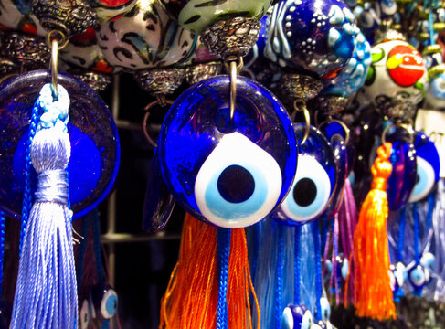 Traditional Turkish Nazar amulets used for protection. Nazar Boncugu Glass ornaments with circular patterns in blue, white, and black, displayed in rows. Close-up of blue evil eye protective amulet