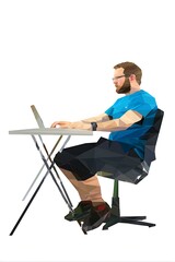 A man sits at a table working on a laptop.