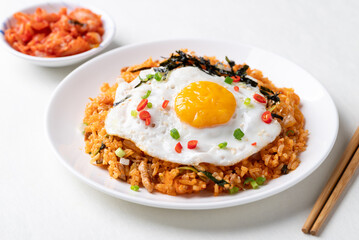 Kimchi fried rice with fried egg, pork, sesame seed, chili, spring onion and seaweed on white plate, Korean food