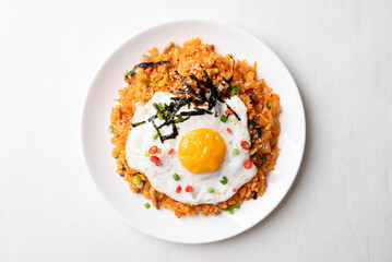 Kimchi fried rice with fried egg, pork, sesame seed, chili, spring onion and seaweed on white plate, Korean food, Top view