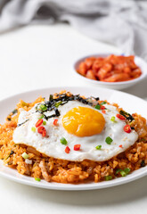Kimchi fried rice with fried egg, pork, sesame seed, chili, spring onion and seaweed on white plate, Korean food