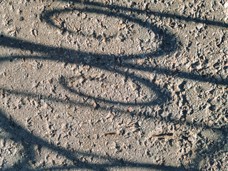 Cinder and gravel in the form of small gray stones and the shadow of a fence lattice, top view. Old...