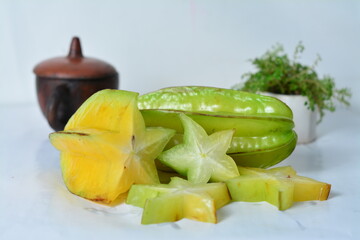 Fresh starfruit (carambola) slices with a whole fruit, styled in a clean setup with clay pot and...