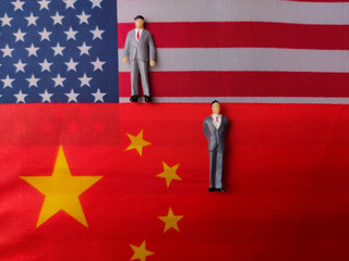 Top view miniature people on a us america and china flag background.Geopolitical concept