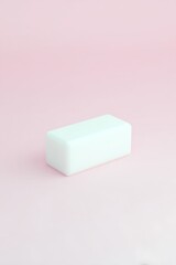 A rectangular, solid white object on a pastel pink background.