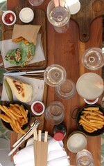 spread of fries, wraps and wine on a wooden table
