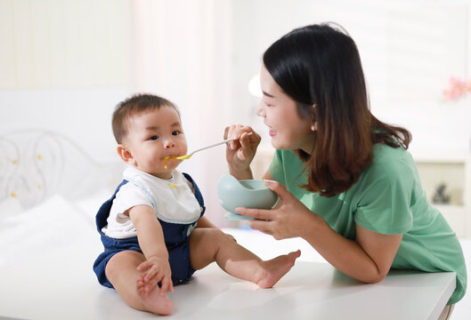 The mother who is feeding her little boy on the table wants to be happy.