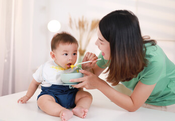 The mother who is feeding her little boy on the table wants to be happy.