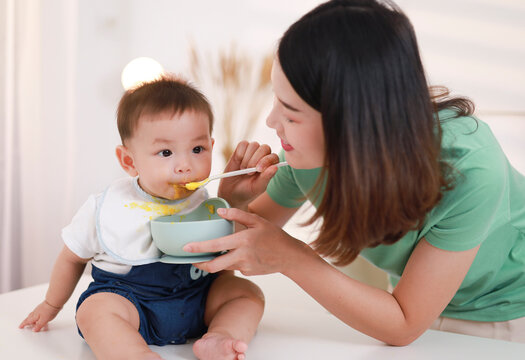 The mother who is feeding her little boy on the table wants to be happy.