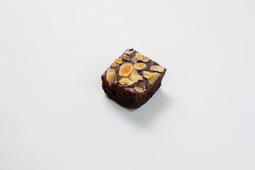 Chocolate Brownie piece with topping almond slice on white background