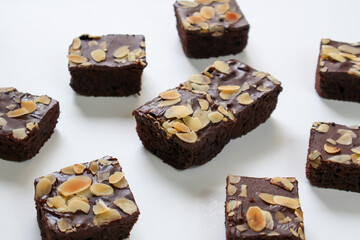 Homemade Chocolate Brownies cake with topping almond slice on white background. side view
