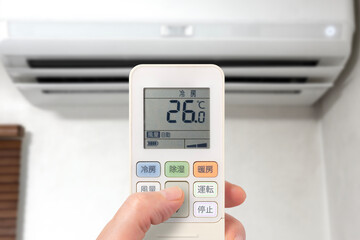 エアコンのリモコンを操作している人