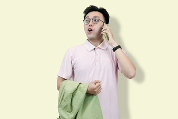 Young Asian man in a casual polo shirt and glasses, holding a jacket over his shoulder, checking...