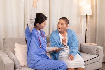 Young nurse in uniform listening attentively to an senior woman on a couch, expressing support and...