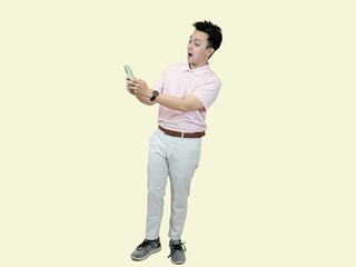 Young happy Asian man wearing a polo shirt and slacks, holding a mobile phone and having a video...