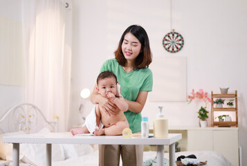 The mother dresses her child, applies powder, combs her hair and applies cream.