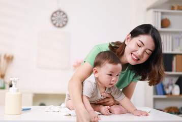The mother dresses her child, applies powder, combs her hair and applies cream.