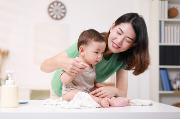 The mother dresses her child, applies powder, combs her hair and applies cream.