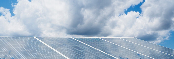 Photovoltaic solar panel illuminated by the sun against a cloudy sky background – green technology