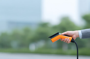 Handheld steam cleaner with orange handle, modern design, outdoor setting, blurred background, cleaning tool, maintenance