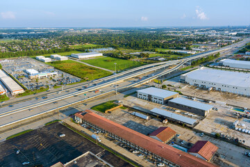 Complex multi level highway intersection with industrial warehouses, parking lots, surrounding suburban landscape in Houston, Harris County, Texas.