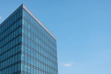 Modern glass building exterior against a clear blue sky showcasing architectural design and urban aesthetics in contemporary city landscape