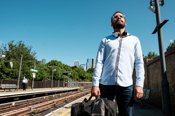 Businessman waiting for train at railway station on sunny day