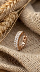 Rose-gold ear cuff encrusted with diamonds contrasts against textured burlap—rich, tactile elegance for upscale fashion narratives.